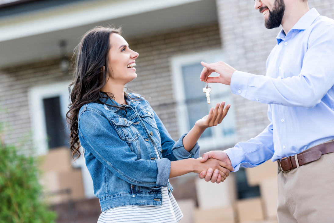 Young happy woman buying new house and taking keys from realtor